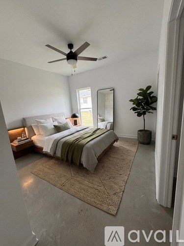 A bedroom with a bed, a rug, a ceiling fan, and a mirror.