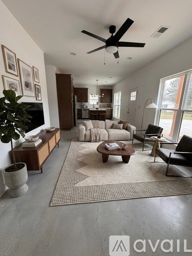 A living room with a ceiling fan and a rug on the floor.