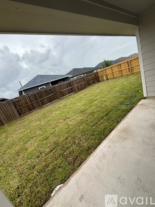 A backyard with a wooden fence and a house in the background.