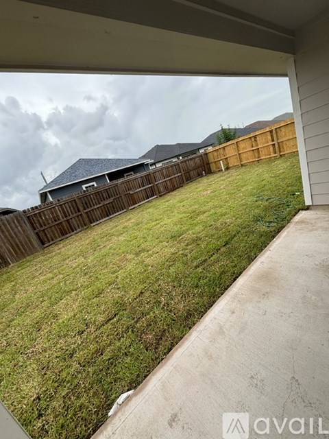 A backyard with a wooden fence and a house in the background.