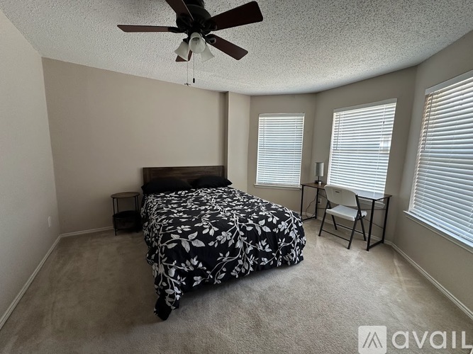 A bedroom with a bed, chair, and ceiling fan.