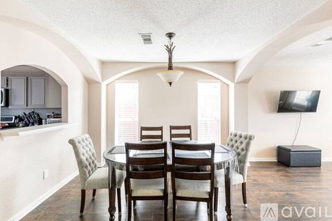 A dining room with a table set for four and a television.
