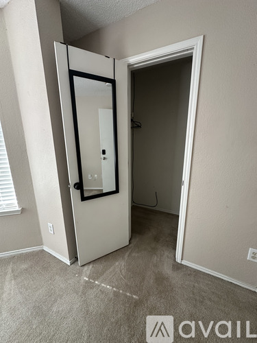 A white door with a black frame is open in a room with carpeted floor.