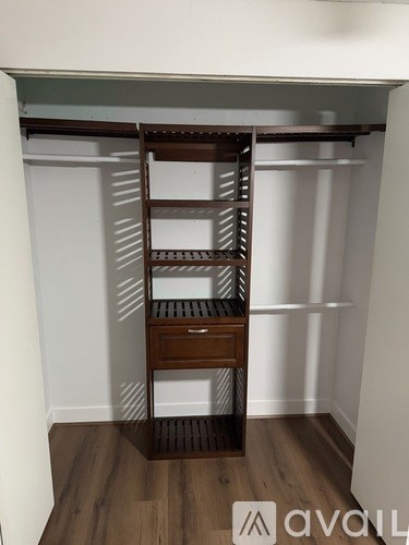 A wooden shelving unit with multiple shelves and a drawer is in a room with white walls.