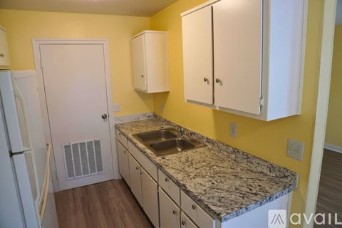 A kitchen with yellow walls and white cabinets.