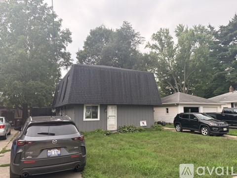A grey house with a black car parked in front.