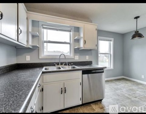 A kitchen with white cabinets and a granite countertop.