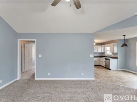 A spacious room with a ceiling fan and a carpeted floor.