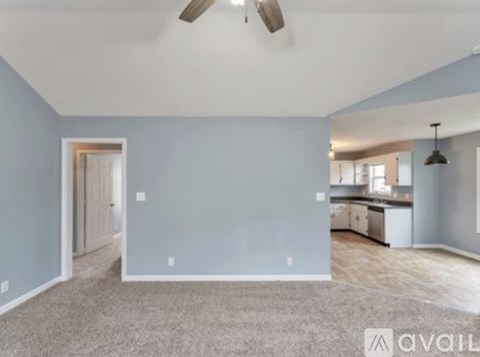 A spacious living room with a ceiling fan and a carpeted floor.