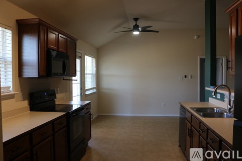 A kitchen with brown cabinets and a black microwave.