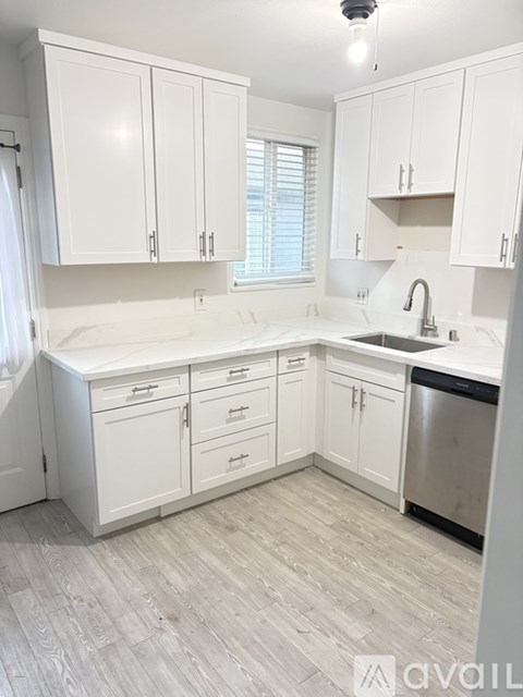 A kitchen with white cabinets and a stainless steel dishwasher.