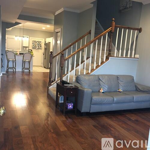 A living room with a grey couch and a wooden staircase.