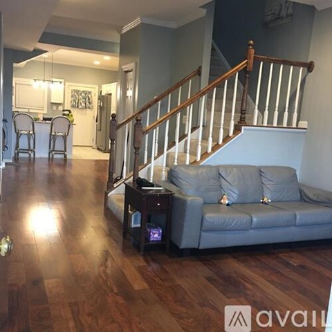 A living room with a grey couch and a wooden staircase.
