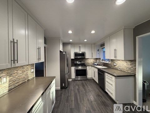 A modern kitchen with stainless steel appliances and wooden flooring.