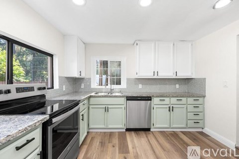 A kitchen with wooden floors and a mix of black and white appliances and cabinets.