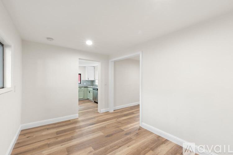A spacious room with wooden flooring and white walls.
