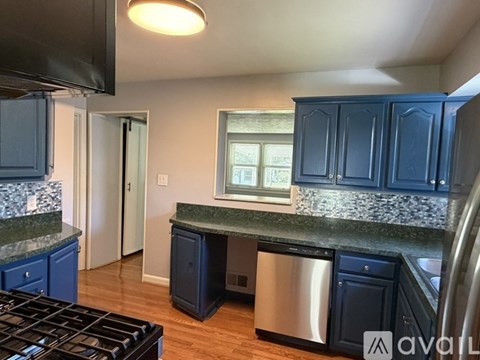 A kitchen with dark blue cabinets and a stainless steel dishwasher.
