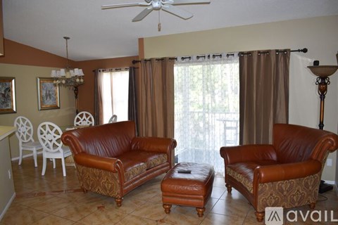 A living room with brown leather furniture and a chandelier.
