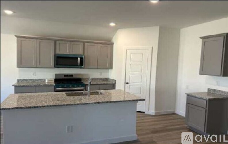 A kitchen with granite countertops and a microwave above the oven.