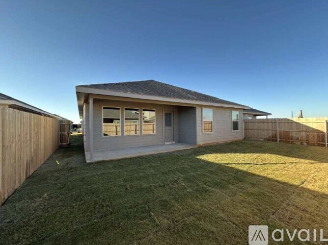 A house with a grey roof and a wooden fence is available for rent.