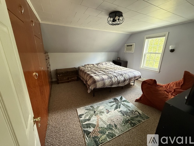 A bedroom with a bed, a chair, and a rug.