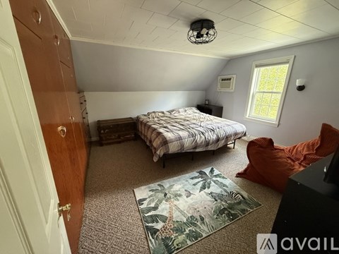A bedroom with a bed, a chair, and a rug.