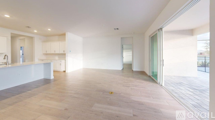 A spacious room with wooden flooring and white walls.