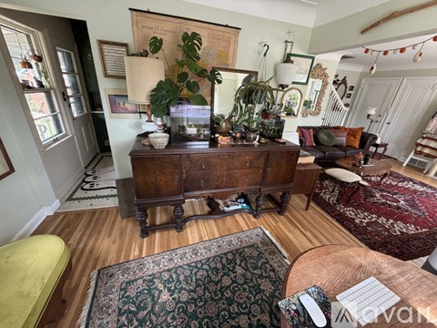 A living room with a wooden table and a green rug.
