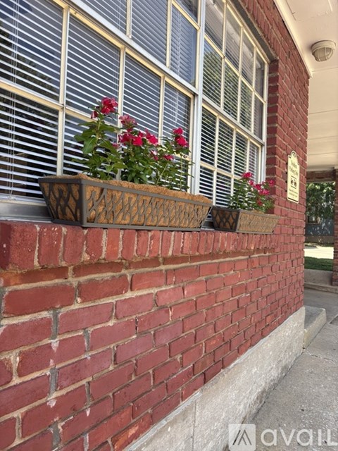 A red brick wall with a window and a planter box with flowers.