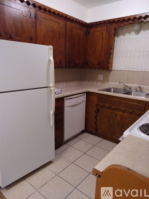 A kitchen with a white fridge and wooden cabinets.