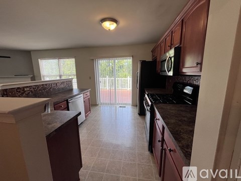 A kitchen with brown cabinets and a black microwave.