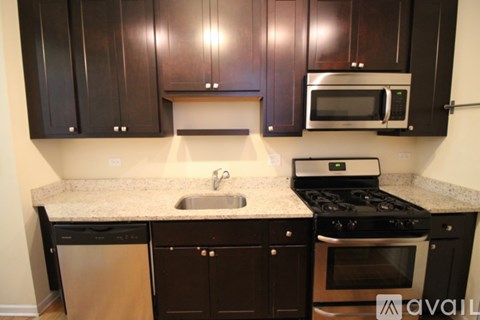 A kitchen with black cabinets and a stainless steel dishwasher.