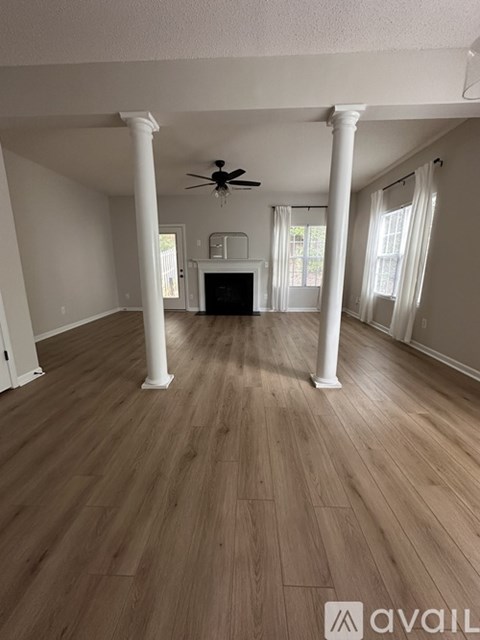A living room with a wooden floor and white columns.