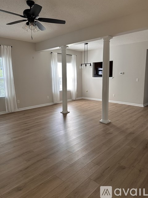 A spacious room with wooden flooring and a ceiling fan.