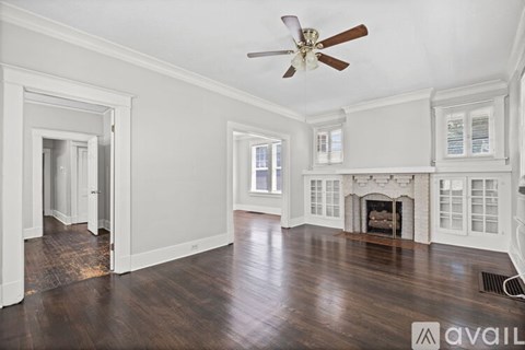 A spacious room with a fireplace and a ceiling fan.