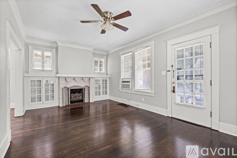 A spacious room with a fireplace and a ceiling fan.