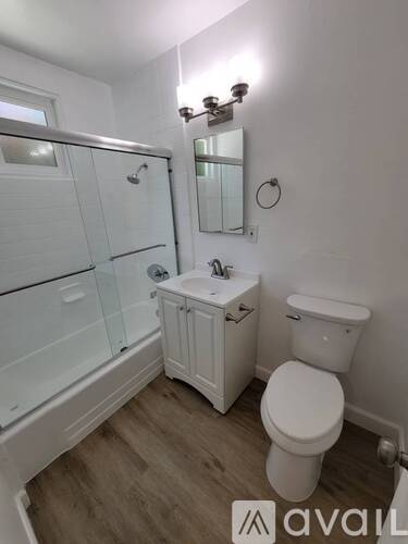 A white toilet sits next to a walk-in shower in a bathroom.