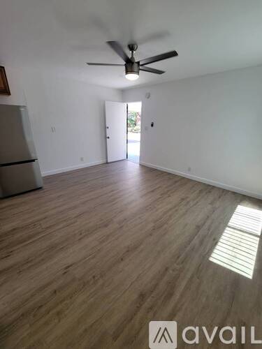 A room with a ceiling fan and a refrigerator.