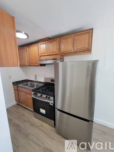 A kitchen with wooden cabinets and a stainless steel refrigerator.