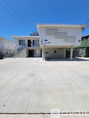 A white two-story house with a garage is situated on a concrete driveway.