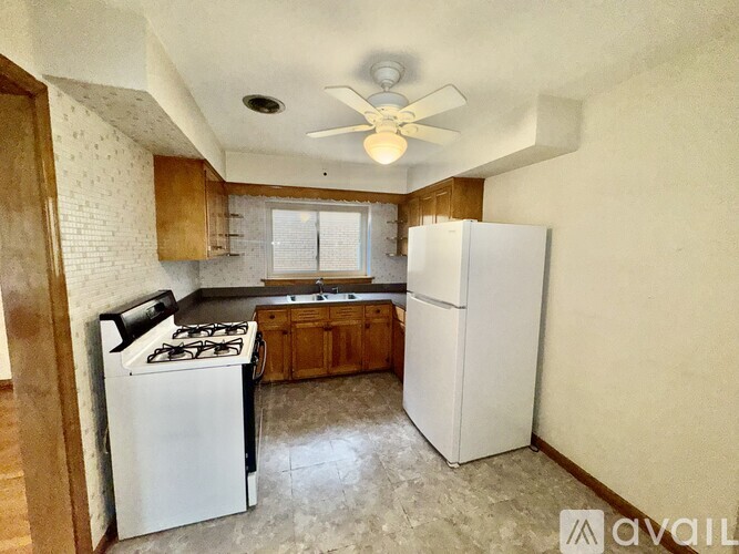 A kitchen with a white refrigerator, white stove, and wooden cabinets.