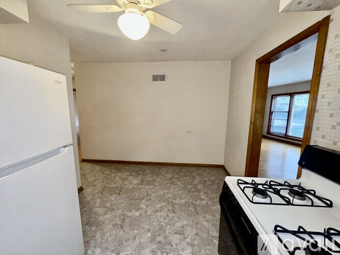 A kitchen with a white fridge, a white stove, and a ceiling fan.