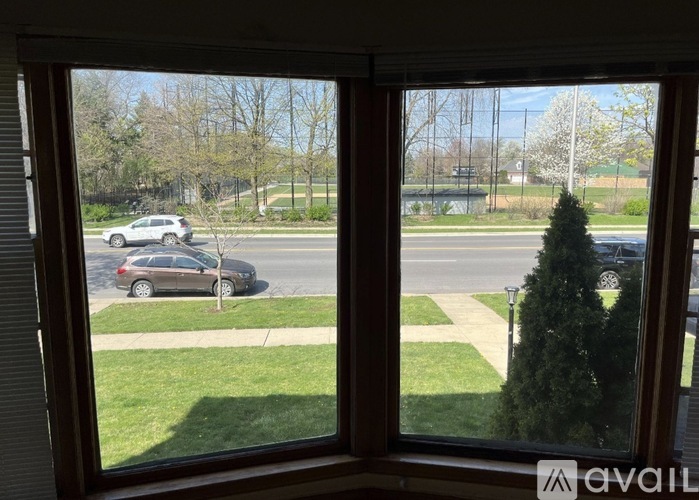 A view from a window looking out at a street with cars and trees.