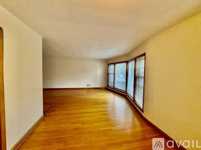 A room with wooden floors and a window with a view of a street.