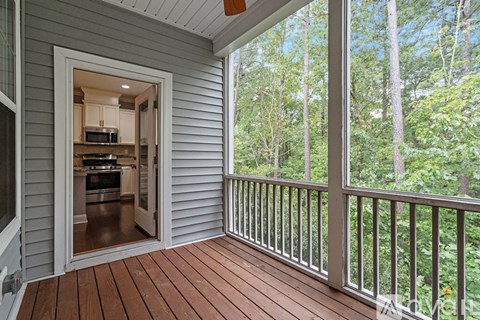 A screened in porch with a wooden floor and a view of trees.