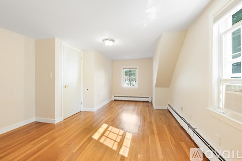 A spacious room with wooden floors and white walls.