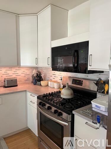 A kitchen with a black microwave, white cabinets, and a stove top oven.
