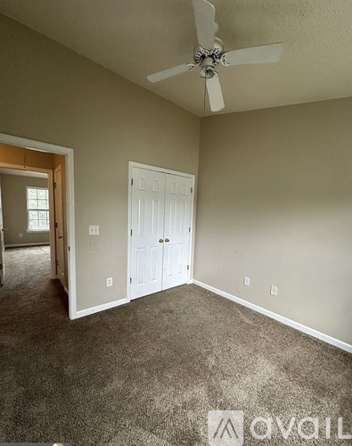 A room with a carpeted floor and a ceiling fan.