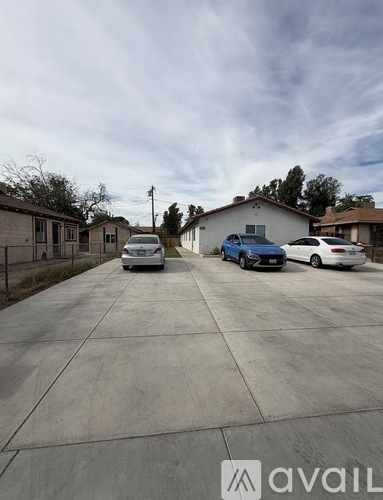 A parking lot with cars and a house in the background.