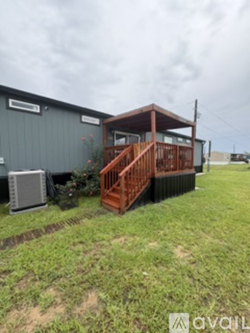 A house with a brown deck is surrounded by grass.